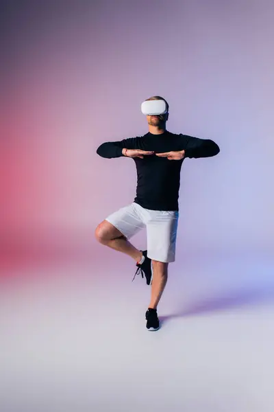 Un hombre con una camisa negra y pantalones cortos blancos ejecuta un movimiento de baile dinámico, mostrando habilidad y pasión en un entorno de estudio. - foto de stock