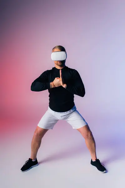 A man wearing a vr stands in front of a pink and blue background, lost in a world of imagination and dreams. — Stock Photo