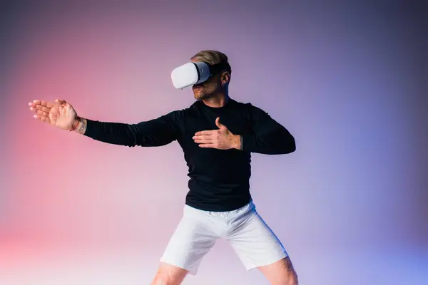 Мужчина в черной рубашке и белых шортах изящно танцует в студии виртуальной реальности. — стоковое фото