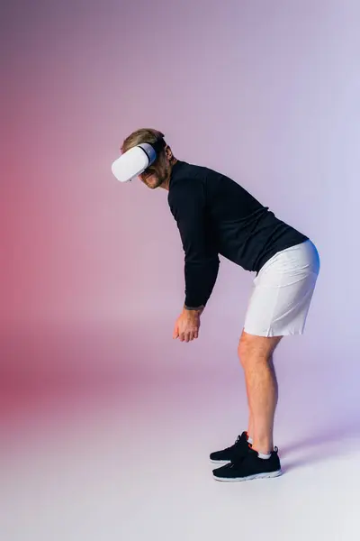 Мужчина в черной рубашке и белых шортах играет в гольф, качается на виртуальном поле. — стоковое фото