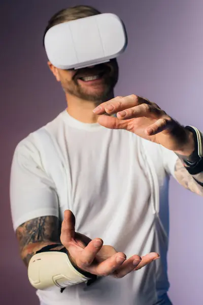 Un hombre con una camiseta blanca explora la realidad virtual en un entorno de estudio con un auricular VR blanco. - foto de stock