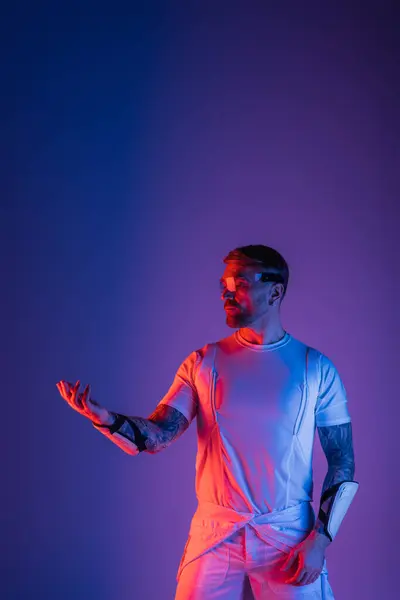 Um homem de camisa branca e calças brancas explora o metaverso usando óculos inteligentes em um estúdio. — Fotografia de Stock