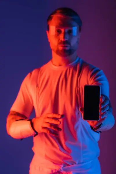 Ein Mann mit intelligenter Brille hält ein Handy in der Hand, eingetaucht in die virtuelle Realität des Metaverse in einem Studio-Setting. — Stockfoto