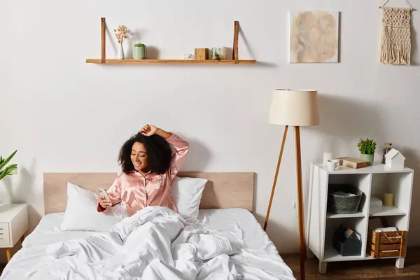 Una riccia donna afroamericana in pigiama riposa pacificamente su un letto con lenzuola bianche nella sua camera da letto. — Foto stock