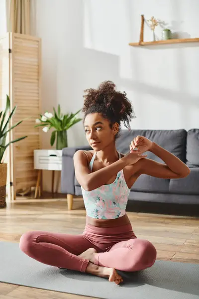 A curly African American woman in activewear practices yoga in her living room, embodying balance and strength. — Stock Photo