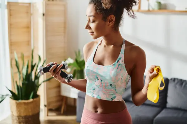 An African American woman in a sports bra top takes a break from her home workout — Stock Photo