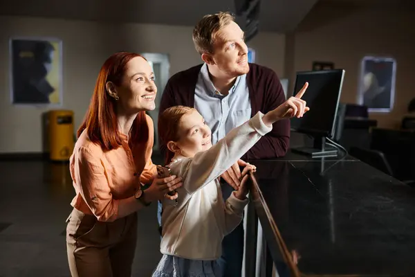 A happy family captivated by something on the cinema wall, engrossed in the moment. — Stock Photo