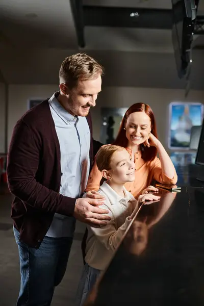 A happy family standing at a concession counter in a cinema, choosing snacks before enjoying a movie together. — Stock Photo