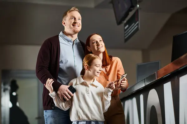 A man, woman, and child gathered together, engrossed in a cell phone screen, smiling and enjoying quality family time. — Stock Photo