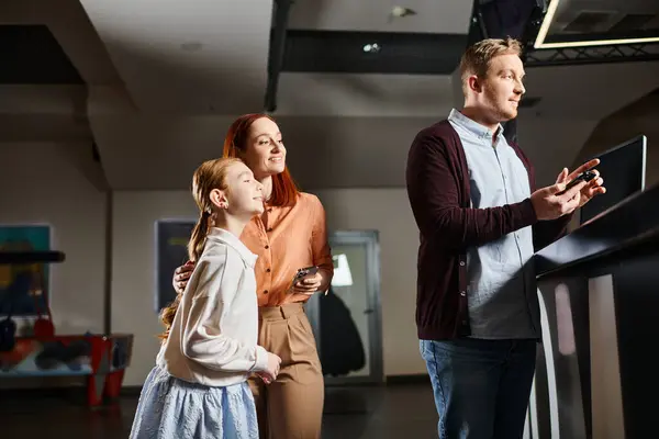 A man, woman, and theit daughter happily stand together, creating joyful memories at the cinema. — Stock Photo