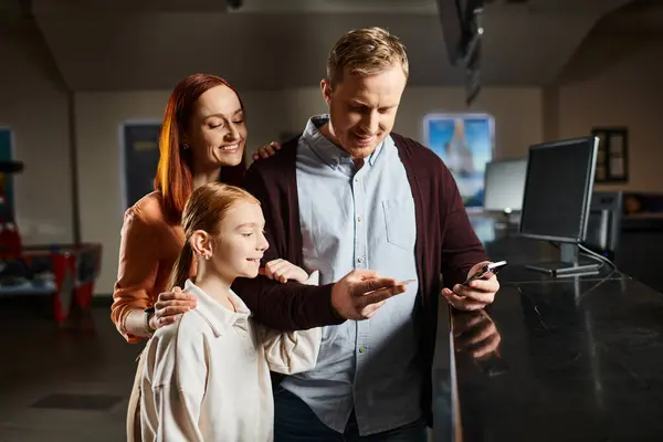 A man and his family share a moment, gathered around a cell phone screen, absorbed in what it shows. — Stock Photo
