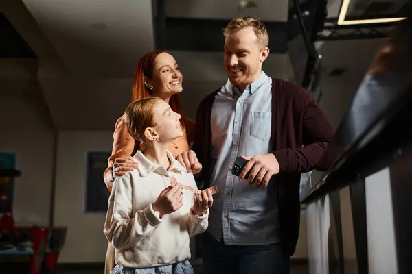 A man and a woman stand together with daughter, embodying unity and love, enjoying a special moment at the cinema as a happy family. — Stock Photo