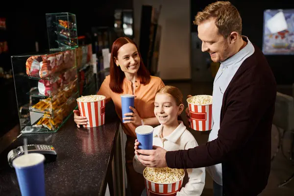 A happy family with a man, a woman, and a child enjoying a movie screening together at the cinema. — Stock Photo