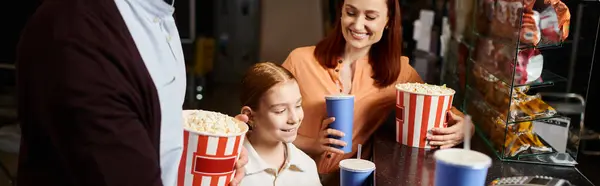 A happy family and friends enjoying popcorn around a table, spending quality time together at a cinema. — Stock Photo