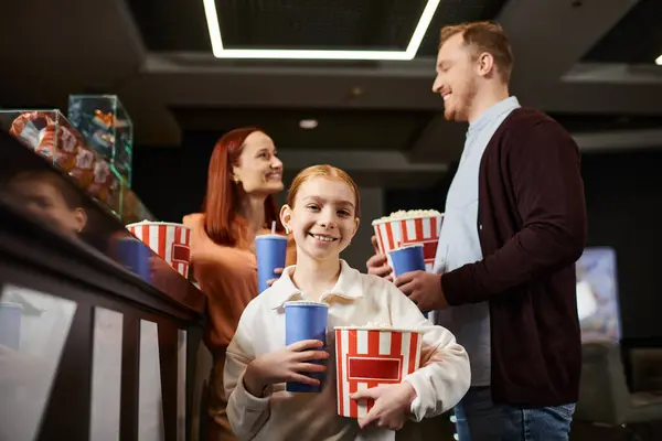Famiglia felice in piedi insieme, tenendo le tazze, godendo di una gita al cinema. — Foto stock