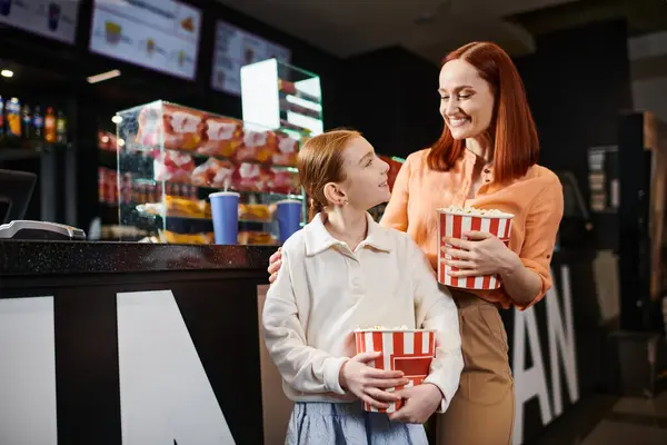 Uma mulher e uma filha estão lado a lado, irradiando alegria e união, compartilhando um momento especial no cinema. — Fotografia de Stock