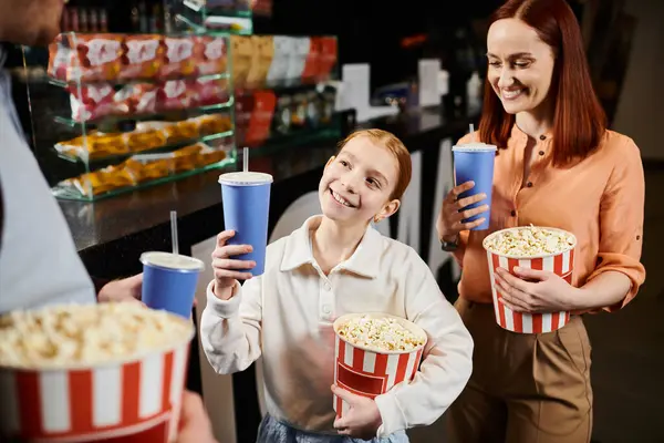 Счастливая семья, стоящая вместе в кругу, держащая ведра попкорна в кинотеатре. — стоковое фото