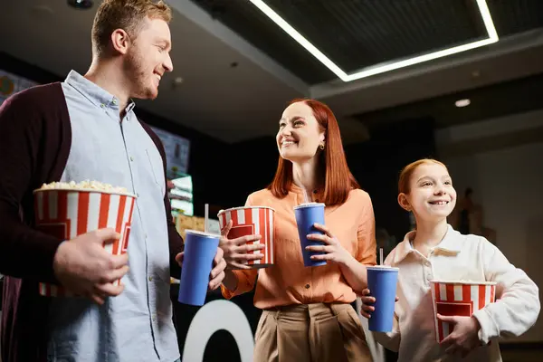 A happy family stands in a circle, holding popcorn while enjoying quality time together. — Stock Photo