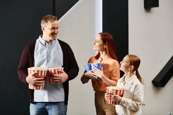 A happy family stands in unity, enjoying a movie night together in a cinema. — Stock Photo