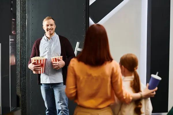 A happy family stands in a circle at the cinema, enjoying each others company while waiting for the movie to start. — Stock Photo