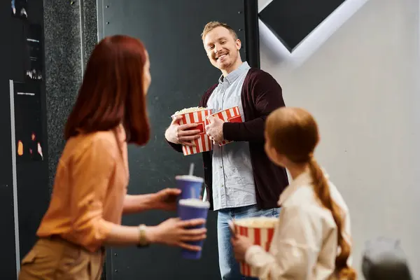 Un uomo si pone fiducioso di fronte a un gruppo di persone, coinvolgendoli in una conversazione o una presentazione in un ambiente cinematografico. — Foto stock