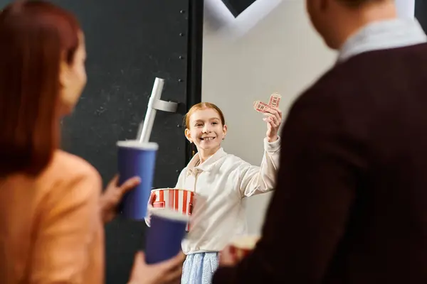 A kid holding popcorn, looking at parents in cinema — Stock Photo