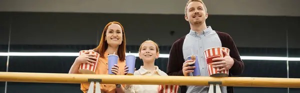 Eine glückliche Familie steht zusammen, hält Tassen in der Hand und genießt einen Filmabend im Kino. — Stockfoto