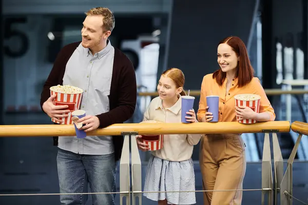 A man, woman, and two children happily holding popcorn while spending quality time together in a cinema. — Stock Photo