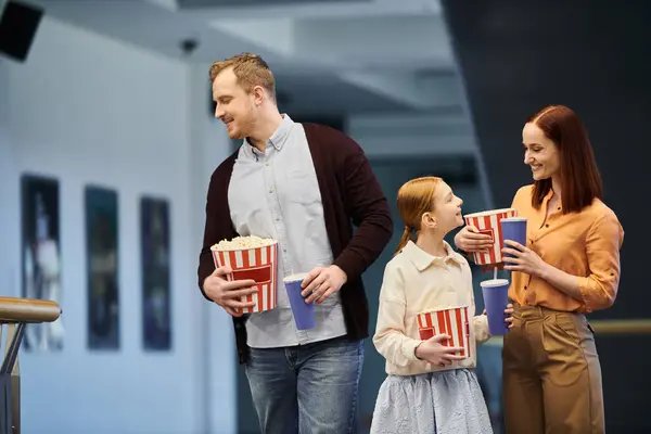 A happy family standing together, holding buckets of popcorn. — Stock Photo