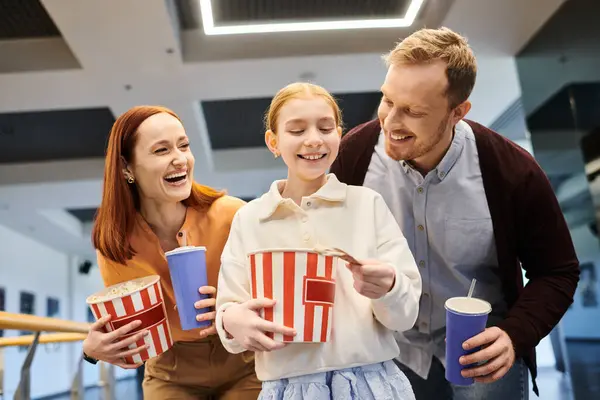Familie hält fröhlich Tassen und Popcorn in der Hand beim Binden während eines Familienfilmabends im Kino. — Stockfoto
