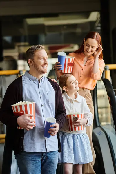 Famiglia godere popcorn mentre a piedi lungo la scala mobile, al cinema, legando come una famiglia felice. — Foto stock