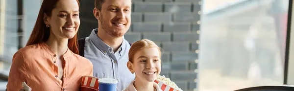 Una famiglia felice in piedi su una scala mobile, sorridente mentre salgono in un cinema. — Foto stock