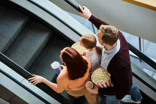 A couple of people enjoying their time together, standing on an escalator, with a backdrop of a bustling cinema. — Stock Photo