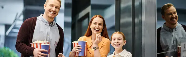 A happy family standing together in a cinema, enjoying a moment of togetherness before watching a film. — Stock Photo