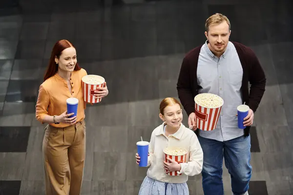 A family happily walks down a street, holding buckets of popcorn after a fun cinema outing — Stock Photo