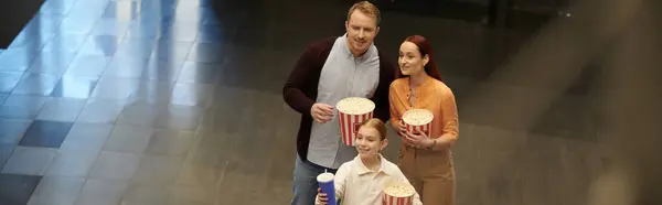 Семья смеется и улыбается, стоя вместе в кинотеатре, создавая незабываемые моменты вместе. — стоковое фото