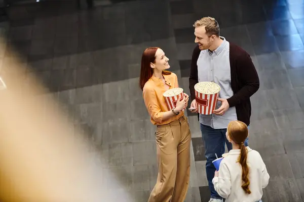 Un uomo e una donna che stanno fianco a fianco, tengono i popcorn, si godono il tempo insieme al cinema. — Foto stock