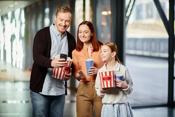 Familie hält freudig Popcorn-Schachteln im Kino in der Hand und schweißt zusammen — Stockfoto