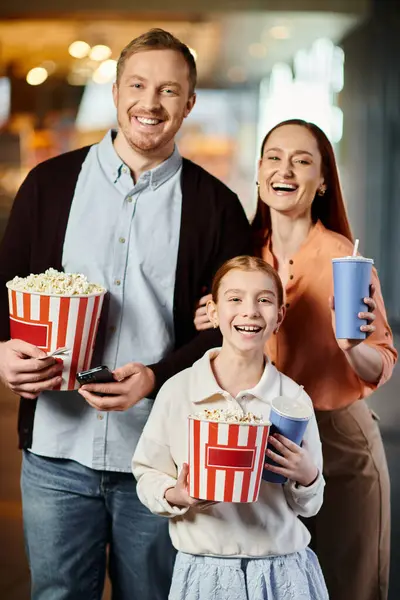 Happy family joyfully holding buckets of popcorn, enjoying a movie together at the cinema. — Stock Photo