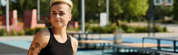 Una joven deportista con el pelo corto y tatuajes se levanta con gracia delante de una piscina, exudando confianza y fuerza. - foto de stock