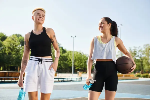 Dos mujeres jóvenes, amigas y jugadoras de baloncesto, se paran confiadas al aire libre. - foto de stock
