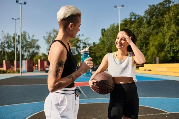 Un hombre y una mujer están de pie con confianza en una cancha de baloncesto, mostrando su atletismo y el trabajo en equipo en un juego animado. - foto de stock