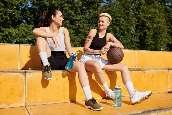 Спортсмени-жінки, молоді жінки, які грають у баскетбол на відкритому повітрі, насолоджуються розслаблюючим моментом разом. — стокове фото