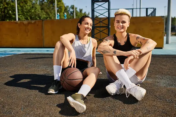 Duas jovens mulheres desfrutam de um momento de tranquilidade em um campo de basquete durante um dia de verão. — Fotografia de Stock