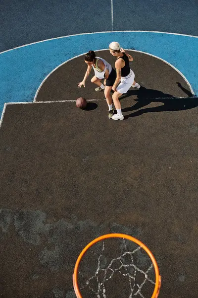 Две девушки в спортивной форме страстно играют в баскетбол на солнечной открытой площадке. — стоковое фото