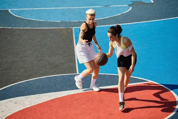 Две молодые женщины уверенно стоят на вершине баскетбольной площадки, готовые взять на игру с решимостью и мастерством. — стоковое фото