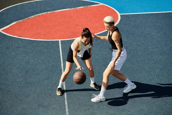 Due giovani donne atletiche stanno orgogliose su un campo da basket, trasudando fiducia e sportività in una giornata di sole.. — Foto stock