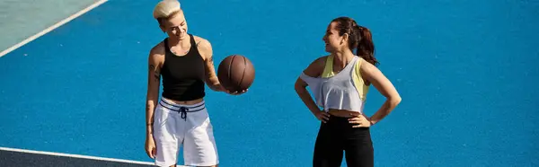 Due amiche atletiche stanno orgogliose in cima a un campo da tennis, crogiolandosi alla luce del sole estivo. — Foto stock