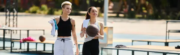 Zwei junge Frauen spielen Basketball auf einem Außenplatz und zeigen unter der Sommersonne ihr sportliches Können und Teamwork. — Stockfoto