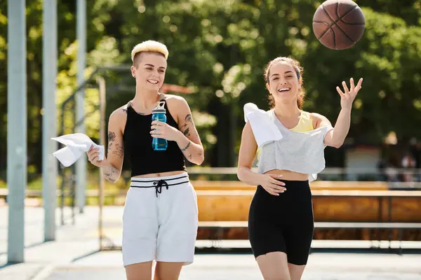 Deux jeunes femmes, amies, jouent au basketball en plein air par une journée ensoleillée d'été. — Photo de stock